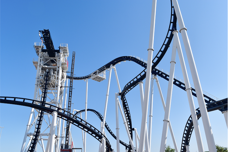 This image showcases the intricate design and structures of a roller coaster, emphasizing its towering loops and curves against a clear sky.